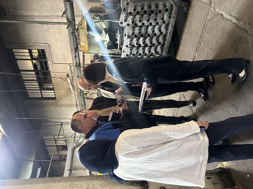 Yueding team discussing metal components with customers during an on-site factory visit