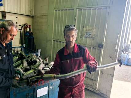 Customer workshop handling a formed exhaust pipe during a Yueding site visit